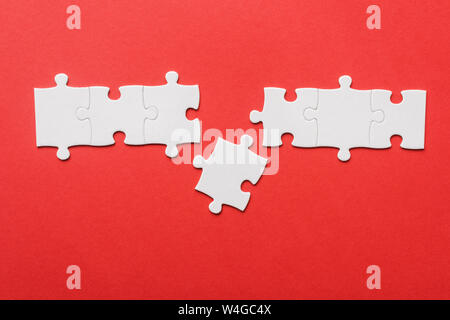 top view of connected jigsaw near puzzle piece on red Stock Photo