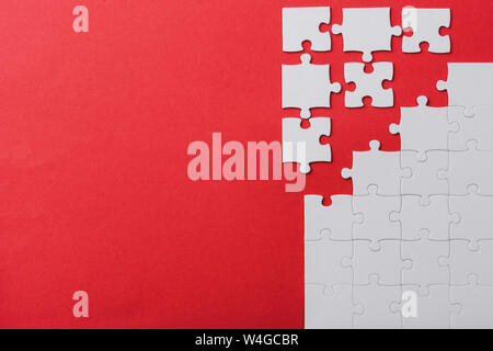 top view of unfinished and white jigsaw puzzle pieces isolated on red Stock Photo