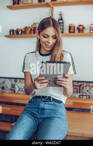 Portrait of young woman smiling using a tablet in a cafe