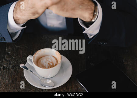 Close-up of businessman with tablet and cappuccino in a cafe Stock Photo