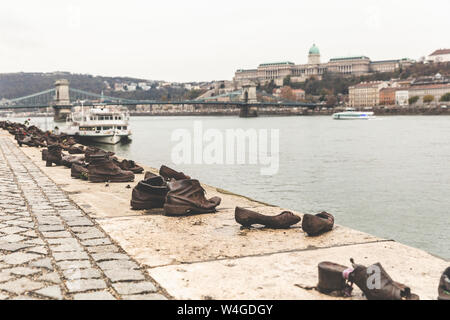 Waterside shoe sculptures, a WWII memorial, with Chain bridge and Buda castle on background, Budapest, Hungary Stock Photo