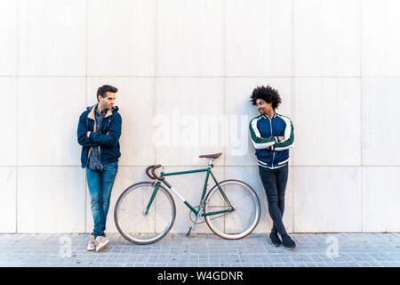 Two casual men with bicycle standing at a wall Stock Photo