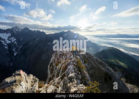 Austria, Tyrol, Gnadenwald, Hundskopf, male climber standing on rock in the morning light Stock Photo