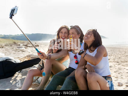 Happy female friends with beer bottles taking a selfie on the beach Stock Photo