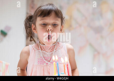 Portrait of little girl blowing out burning candles on her birthday cake Stock Photo