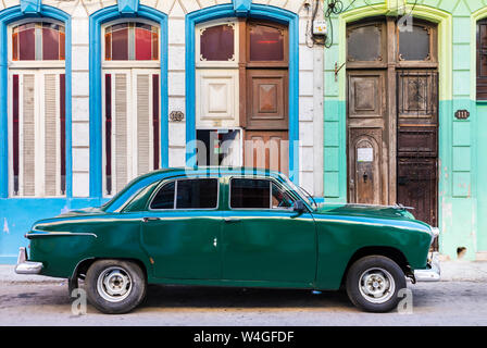 Green vintage car parked in front of house entrances, Havana, Cuba Stock Photo