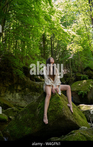 Young woman sitting on a rock in the forest, Garrotxa, Spain Stock Photo