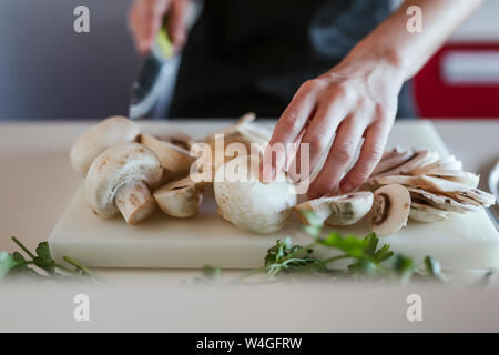 Young woman's hands preparing champignons, close-up Stock Photo