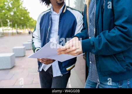 Close-up of two casual businessmen discussing paper in the city, Barcelona, Spain Stock Photo