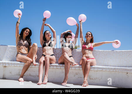 Girlfriends celebrating birthday, sitting on bench with balloons Stock Photo