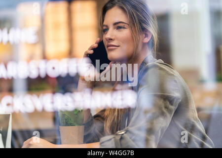 Young businesswoman in a cafe, seen through window Stock Photo