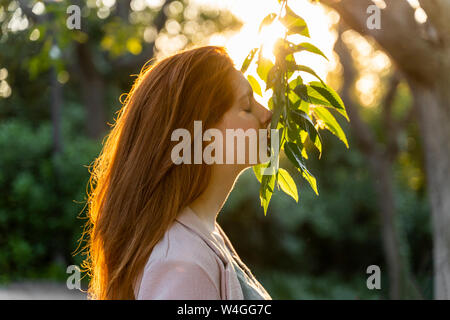 Young redheaded woman with face on leaves Stock Photo