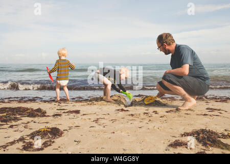 Father with two kids playing on the beach
