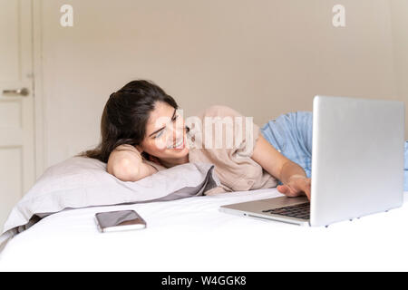 happy young woman lying with laptop on bed Stock Photo - Alamy