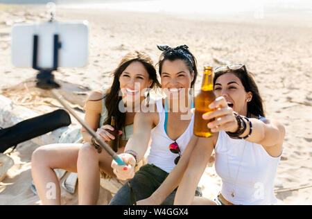 Happy female friends with beer bottles taking a selfie on the beach Stock Photo