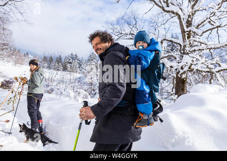 Father with son in the child carrier, mother and dog in Oberammergau in winter Stock Photo