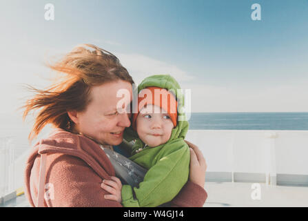 Mother carrying baby boy in a sling on a ferry Stock Photo