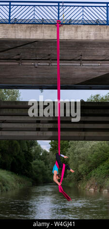 Young woman doing aerial silk on a bridge Stock Photo