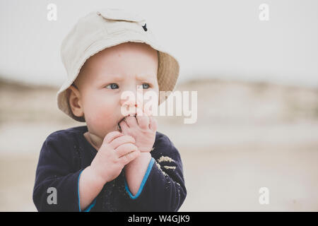 Baby boy eating sand on the beach Stock Photo