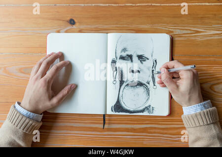 Man painting an African with lip plate Stock Photo