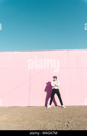 Young man in front of pink construction barrier, looking away Stock Photo