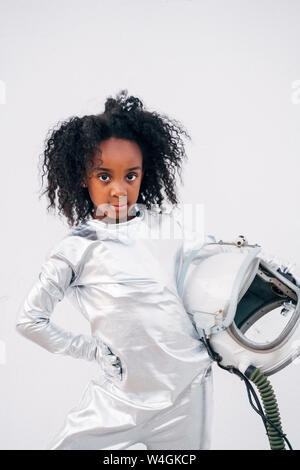 Portrait of little girl with space hat wearing space suit in front of white background Stock Photo