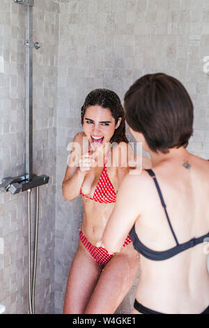 Young women enjoying the summer time at pool, playing under the shower Stock Photo