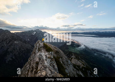 Austria, Tyrol, Gnadenwald, Hundskopf, male climber standing on rock in the morning light Stock Photo