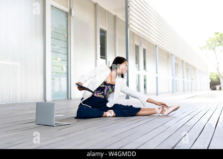 Female balett dancer sitting on the ground, using tablet and laptop Stock Photo