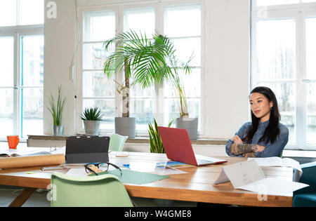 Woman using laptop at table in modern office Stock Photo