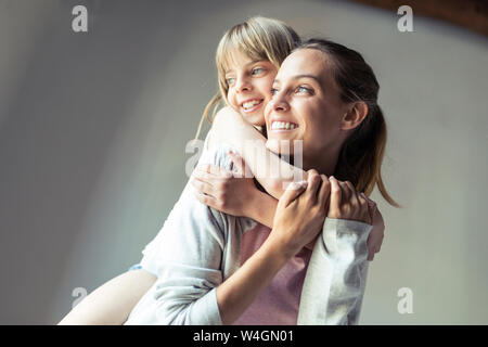 Mother and daughter playing at home, piggyback Stock Photo
