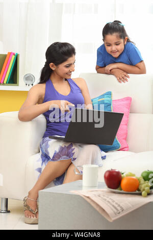 Woman using a laptop to her daughter Stock Photo