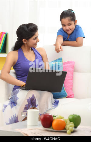Woman using a laptop to her daughter Stock Photo