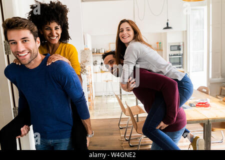 Happy men carrying women piggyback at home Stock Photo