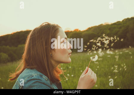 Profile of teenage girl blowing blowball Stock Photo