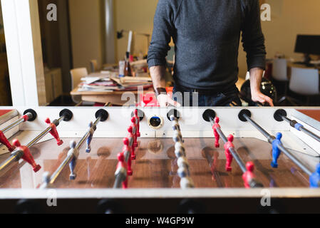 Close-up of man playing foosball in office Stock Photo