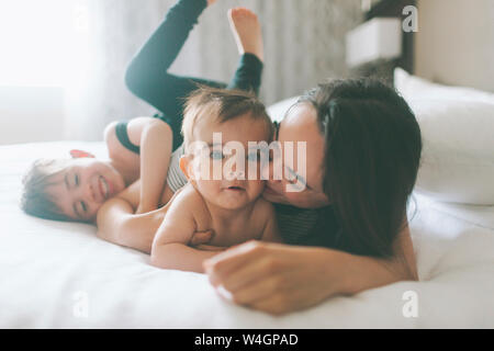 Mother and two boys cuddling in bed at home Stock Photo