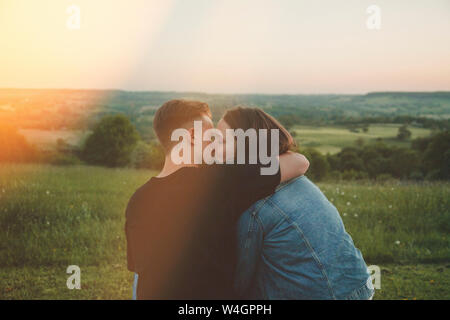 Back view of happy young lovers kissing at sunset Stock Photo