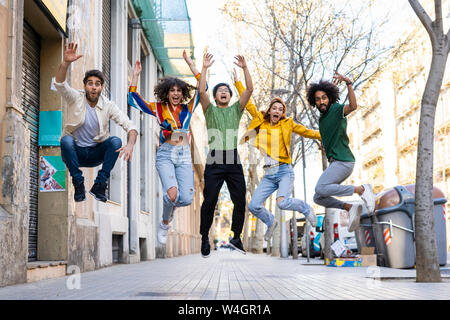 Happy group of friends having fun in the city jumping mid-air Stock Photo