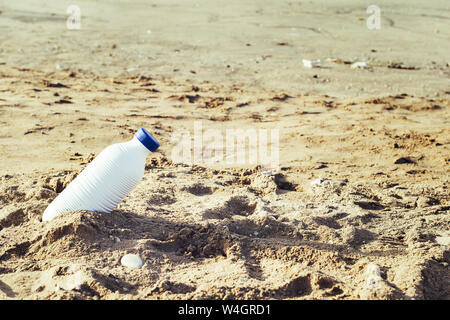 white plastic bottle lies on the sand of the beach and pollutes the sea and the marine life, concept of pollution control of the oceans by plastic Stock Photo