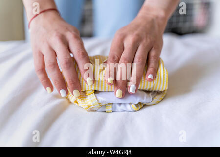 Close-up of woman folding clothes on bed