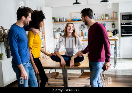 Four happy friends at dining table at home Stock Photo