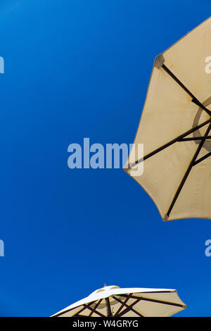 sun umbrellas against a blue sky Stock Photo