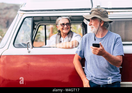 Senior couple traveling in a vintage van, using smartphone Stock Photo