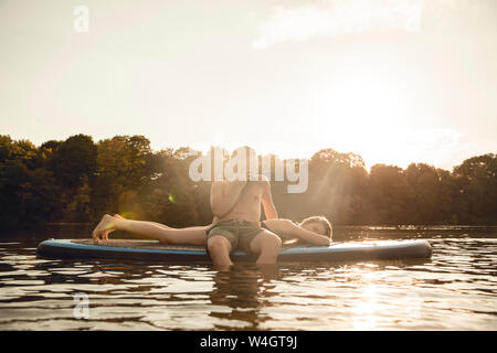 Youple on the lake, relaxing on a paddleboard, man talking on the phone Stock Photo