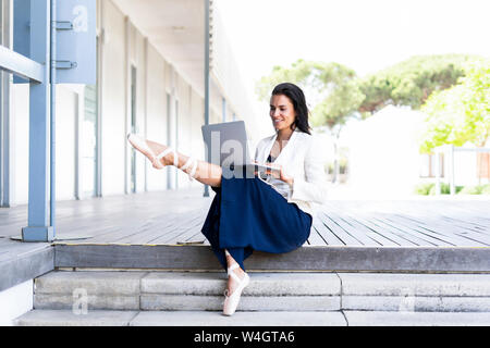 Female ballet dancer using laptop sitting on steps Stock Photo