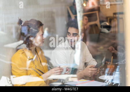 Man and woman with cell phone and notebook meeting in a cafe