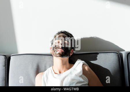 Relaxed young woman wearing facial mask at home Stock Photo