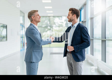 Two businessmen shaking hands in a passageway Stock Photo