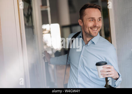 Businessman leaving coffee shope with take out coffee Stock Photo